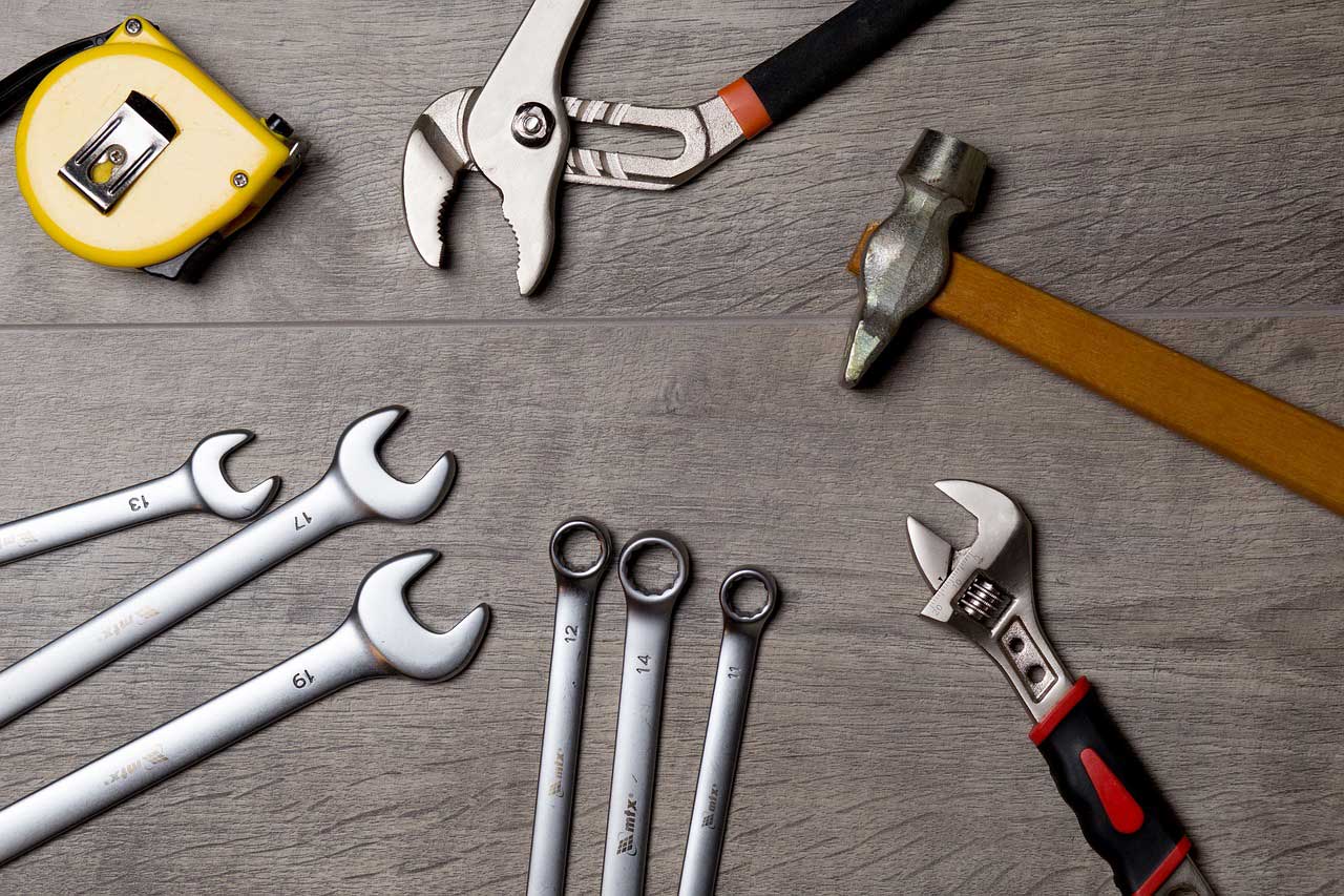 A handful of wrenches and other tools spread out on a grey workbench